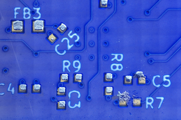 Closeup of several SMT pad showing solder paste deposits. All are displaced slightly to the northeast of center, one pad has almost no paste on it. Several others show signs of smearing.