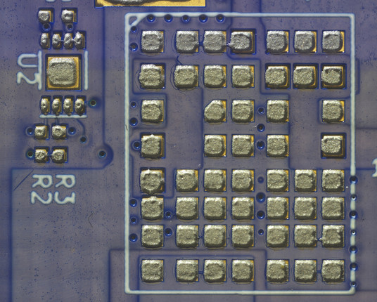 High resolution view of LGA DC-DC converter footprint showing solder paste deposits. A few of the deposits have small tendrils reaching out towards adjacent pads that might increase the risk of a short.