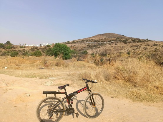 a photo of a folding bike on the road where there is a hill at the background many meters high