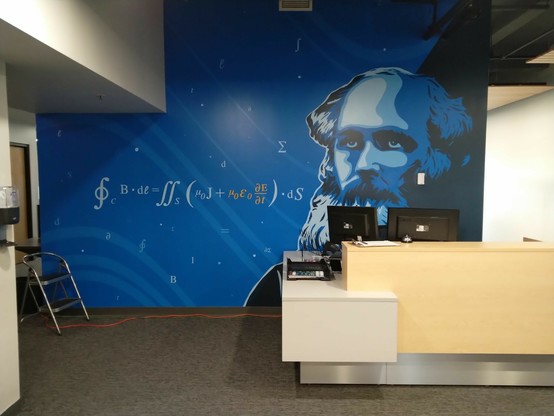 Corporate reception desk with a mural behind it featuring James Clerk Maxwell and his equations