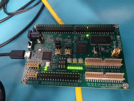 Green dev board with lots of pin headers for IO and a bunch of glowing green LEDs