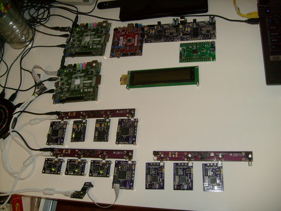 My desk in early 2013 featuring a bunch of Digilent devkits plus three of these bar-shaped hubs in a row, each with four tiny dev boards hanging off them. One port is free, showing the male mini-B connector protruding