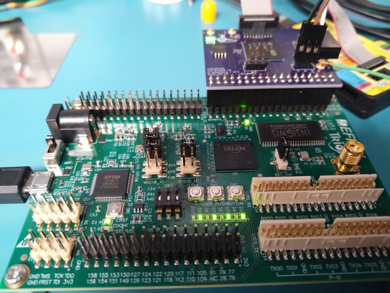 Efinix Trion T20 devkit with alternating on/off LED pattern displayed and a small purple PCB hanging off one of the IO connectors
