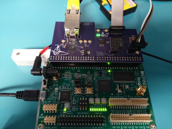 Small purple PCB with an Ethernet connector hanging off a large green FPGA devkit