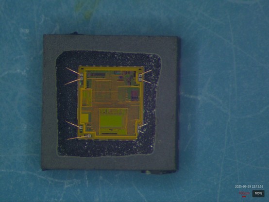 Top down view of a small square IC package after etching away molding compound to expose the silicon die inside. Eight tiny copper wires run from pads on the die perimeter into the package where they connect to (unseen) solder terminals on the underside