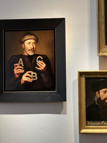 A photo of one of three portraits of Gutenberg at his museum.  He is holding the letters A, B and C using three hands.