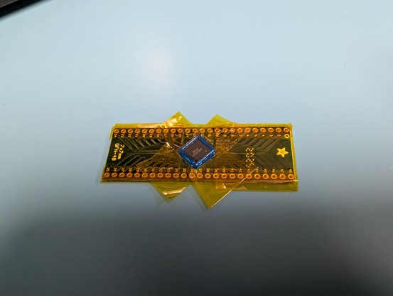 QFN surrounded by rubber mask and kapton tape, soldered to a PCB