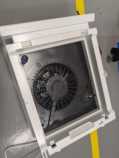 Air purifier partially opened up with a screwdriver in one of the screw sockets