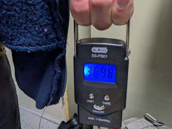 Spring scale showing the pack weighs 36.46 pounds