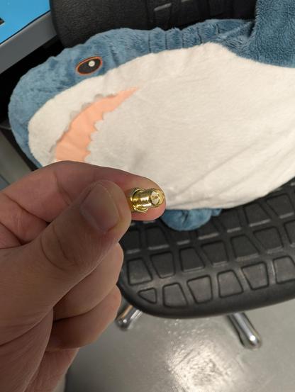 An RP-SMA female connector held up in front of a blahaj sitting on a lab chair.

Despite nominally being a female connector, it has a protruding center contact.