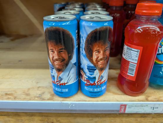 Cans of Bob Ross Positive Energy Drink on a store shelf