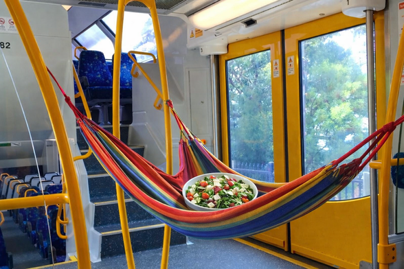 a photoshopped image of a hammock, holding a salad, inside a Tangara train carriage