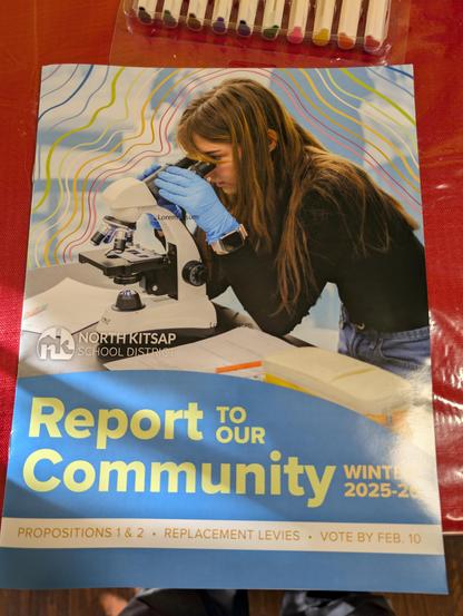 Community report from the local school district. The cover features a probably stock photo of a woman wearing blue lab gloves and looking into a microscope