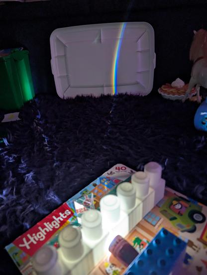 Crude spectrometer made from mega bloks as a slit, a handheld flashlight, and a prism sitting on a book